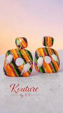 Load image into Gallery viewer, Close-up of a colorful polymer clay dangle earring with white ghost artwork, glitter accents, and bright stripes